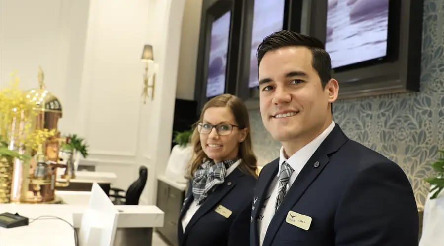 Two individuals in business suits stand beside a desk Condor Ascent
