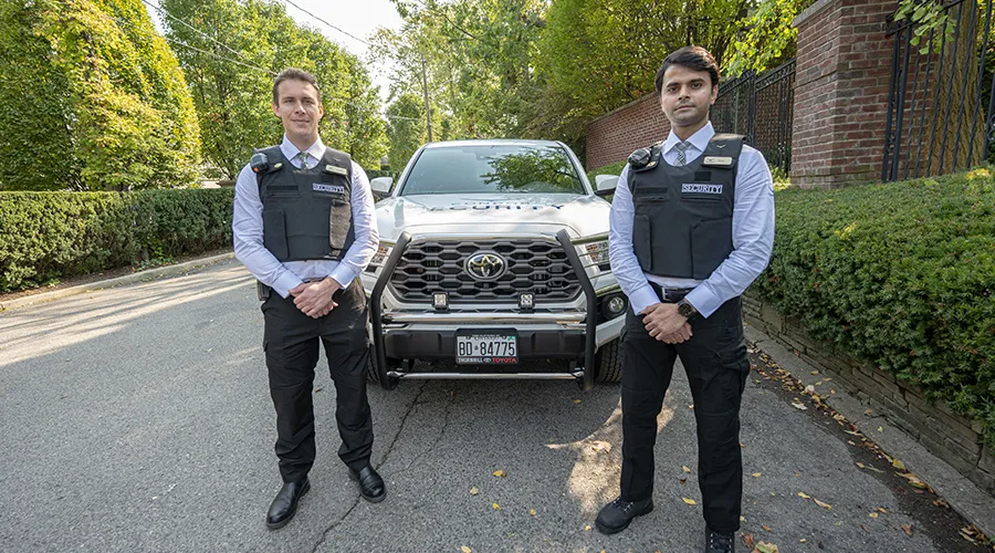 Two security guards are standing in front of a vehicle-Condor Security (Security Services)